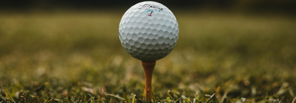 Close-up of a golf ball on a tee in the grass.