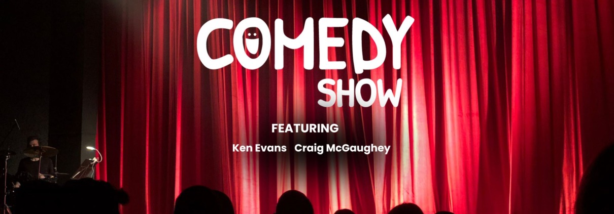 Stand-up comedy show with a microphone on stage and red curtains.